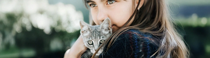 Ein Mädchen hält eine Katze auf dem Arm.